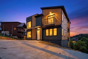 Een modern huis met twee verdiepingen, een balkon, een oprit en uitzicht op de omgeving.