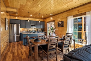 A wooden interior with a kitchen, dining area, and large windows. - Just Relax Retreat! View, Game, Indoor Heated Pool, Theatre, Hottub, Location (Sevierville)