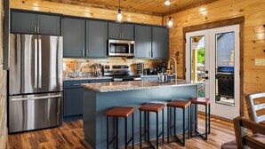 Eine moderne Küche mit Edelstahlgeräten, einer Bar mit Hockern und einer Holzbalkendecke.