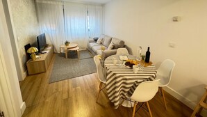 Ein kompakter Wohnraum mit Essbereich, einer Couch, einem Fernseher und einem kleinen Tisch mit einer Pflanze.