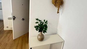 Ein Zimmer mit einer weißen Tür, einem weißen Konsolentisch mit einer Pflanzvase und einem dekorativen Wandelement.
