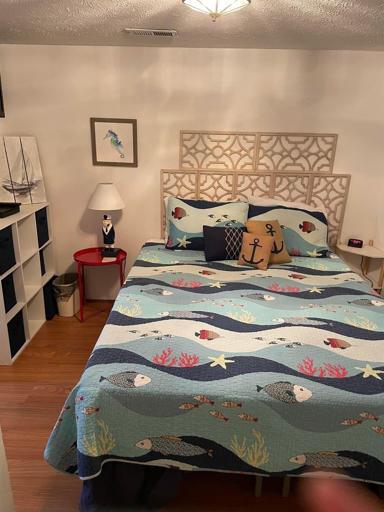 Ein Schlafzimmer mit einem Bett, einem Nachttisch, einer Lampe, einem Bücherregal und einer Wanduhr.