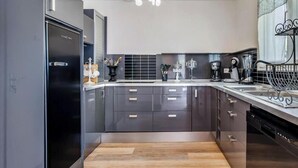 A modern kitchen with a black refrigerator, a coffee machine, and a sink. - Gîtes de France® - La Margautine (VEULETTES SUR MER)