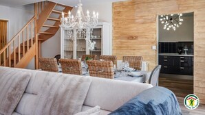 A modern living room with a staircase, dining area, and kitchen. - Gîtes de France® - La Margautine (VEULETTES SUR MER)