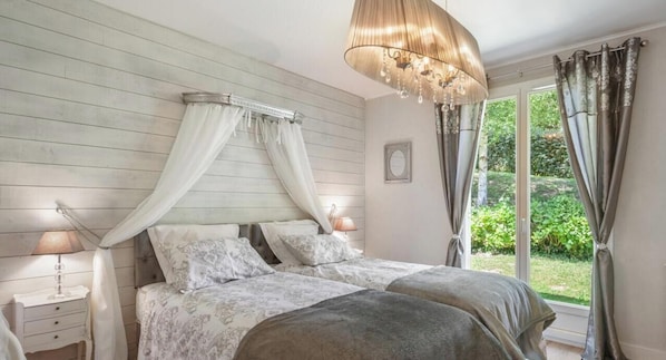 Ein Schlafzimmer mit Himmelsbett, Nachttischlampen und Blick ins Grüne.