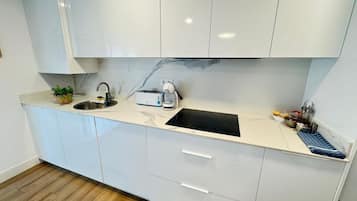 Una cocina moderna con armarios blancos, encimera negra, un fregadero, un tostador y una cafetera.