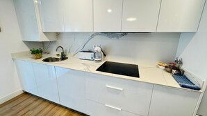 A modern kitchen with white cabinets, a black countertop, a sink, a toaster, and a coffee maker. - PRECIOSOS APARTAMENTOS RIOJALAND EN LARDERO (Lardero)
