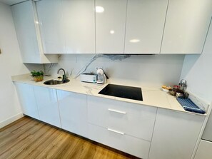 Eine moderne Küche mit weißen Schränken, einer schwarzen Arbeitsplatte, einem Spülbecken, einem Toaster und einer Kaffeemaschine.