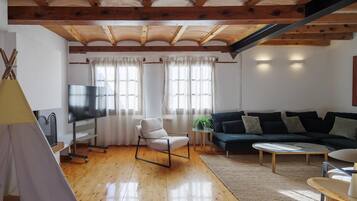 Un salon avec un plafond en bois, un canapé, un téléviseur et une structure ressemblant à une tente.