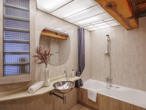 A modern bathroom with a bathtub, a sink, a mirror, and a shower.