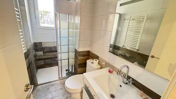 Une salle de bain comprenant des toilettes, un lavabo et un espace douche.