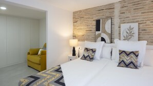 A bedroom with a bed, a nightstand, a lamp, a chair, and a brick wall. - CASA BOUTIQUE SAN JUAN (LOGROÑO)