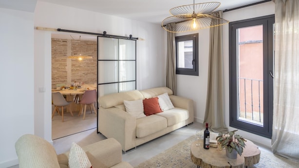 A modern living room with a sofa, a dining area, and a sliding glass door to the outside. - CASA BOUTIQUE SAN JUAN (LOGROÑO)