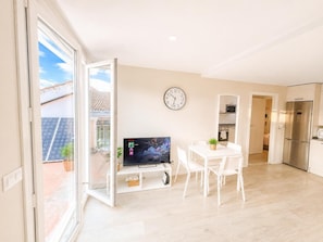 Un apartamento moderno con comedor, televisor y cocina.