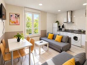 A modern apartment with a dining area, sofa, and kitchen. - APARTAMENTOS LOGROÑO CENTRO (LOGROÑO)