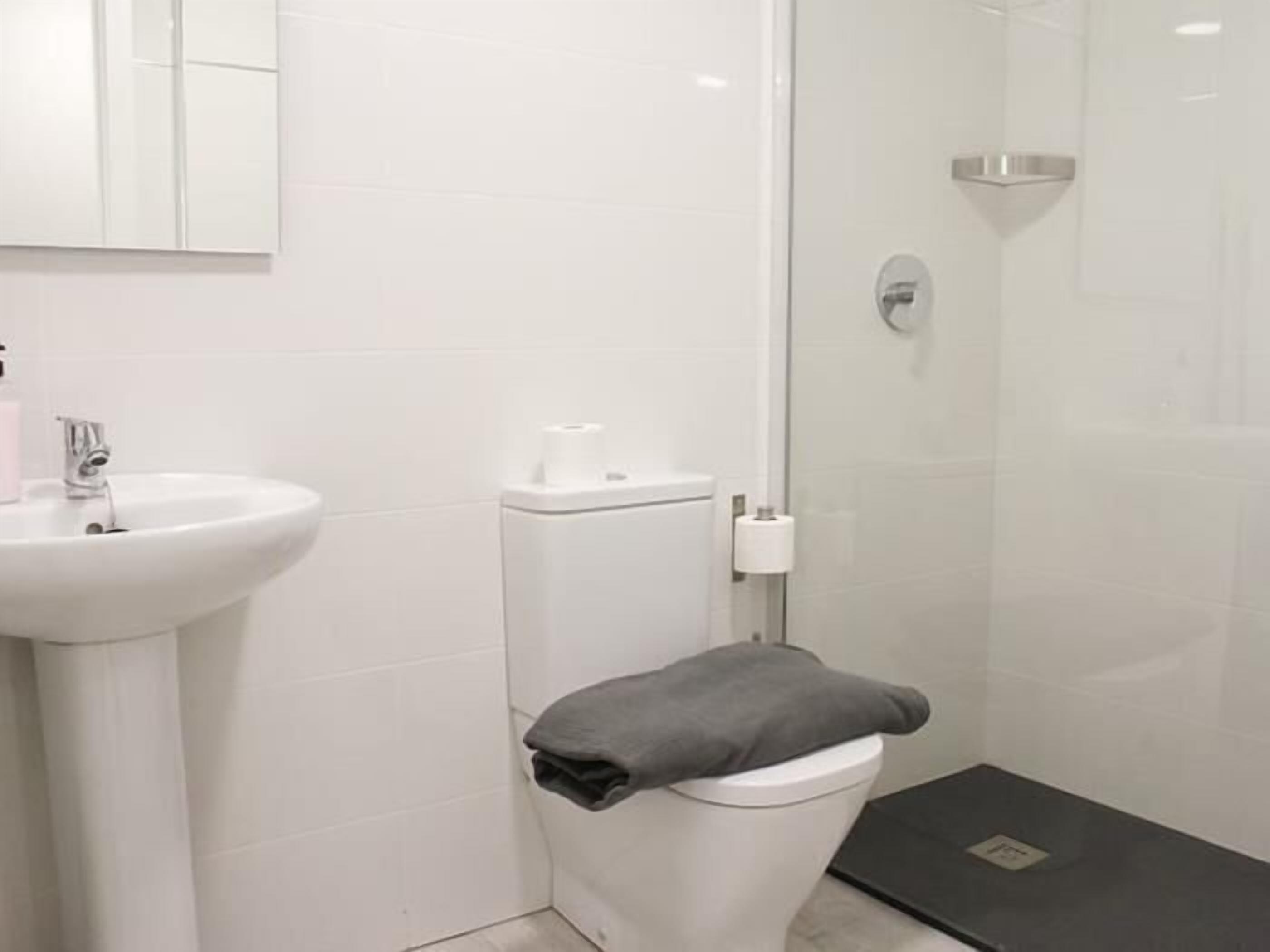 A modern bathroom with a white sink, toilet, and shower.