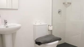 A modern bathroom with a white sink, toilet, and shower.
