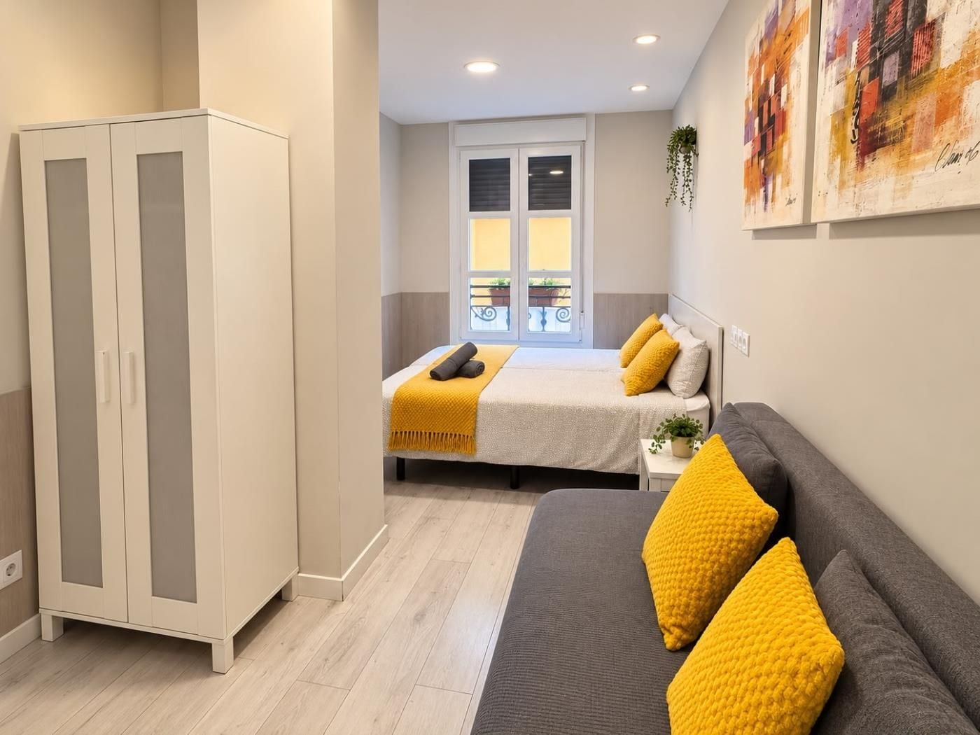 Un dormitorio con cama, sofá, armario y ventana con persianas.