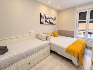 Ein Schlafzimmer mit zwei Betten, einem Bild an der Wand und einem Fenster mit Jalousien.