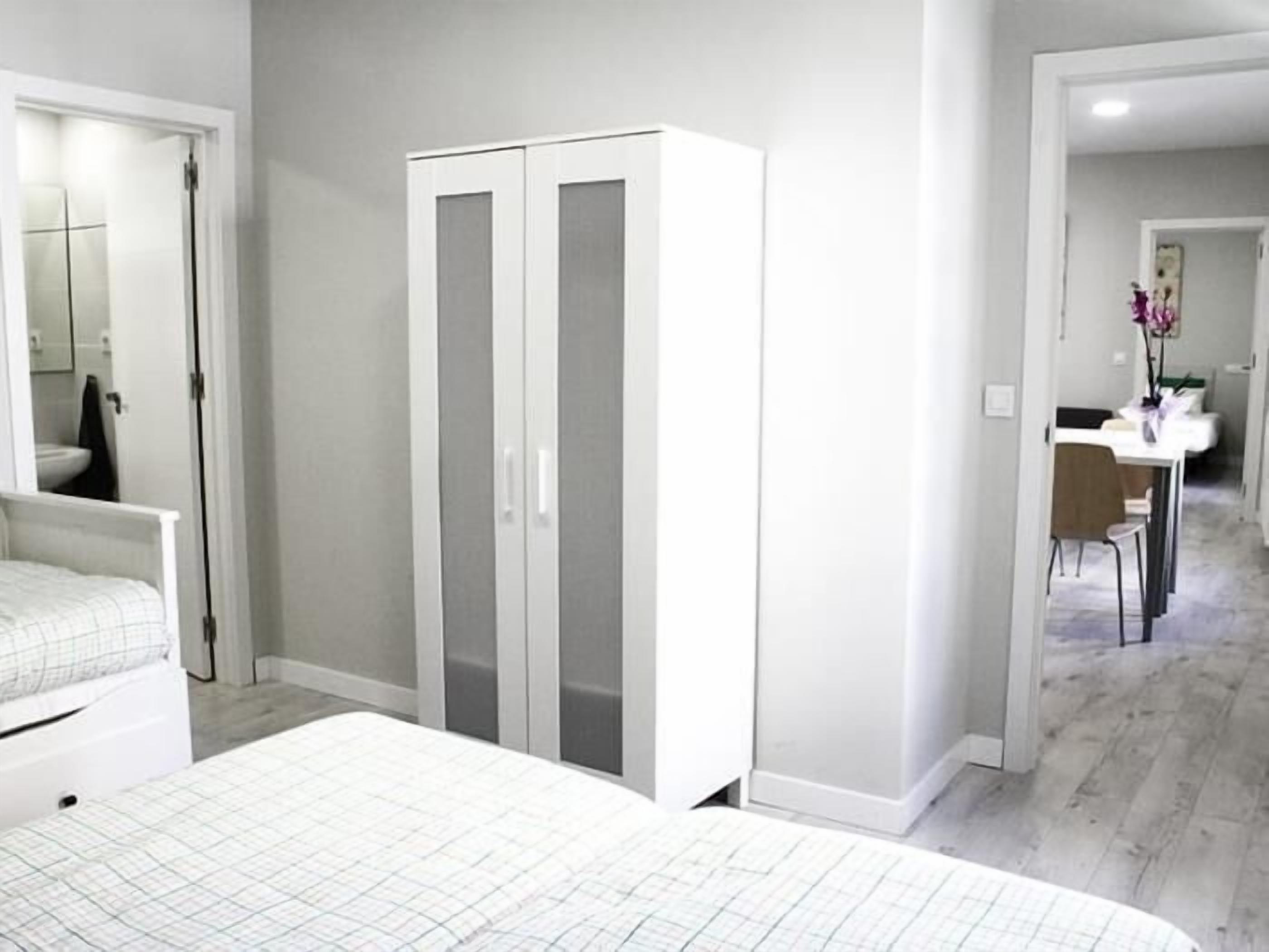 A bedroom with a bed, a wardrobe, and a bathroom visible through an open door.