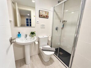 Ein modernes Badezimmer mit Waschbecken, Toilette und einer Duschkabine.