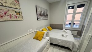 Une chambre avec deux lits simples, une fenêtre donnant sur un beau paysage et des œuvres d’art accrochées aux murs.