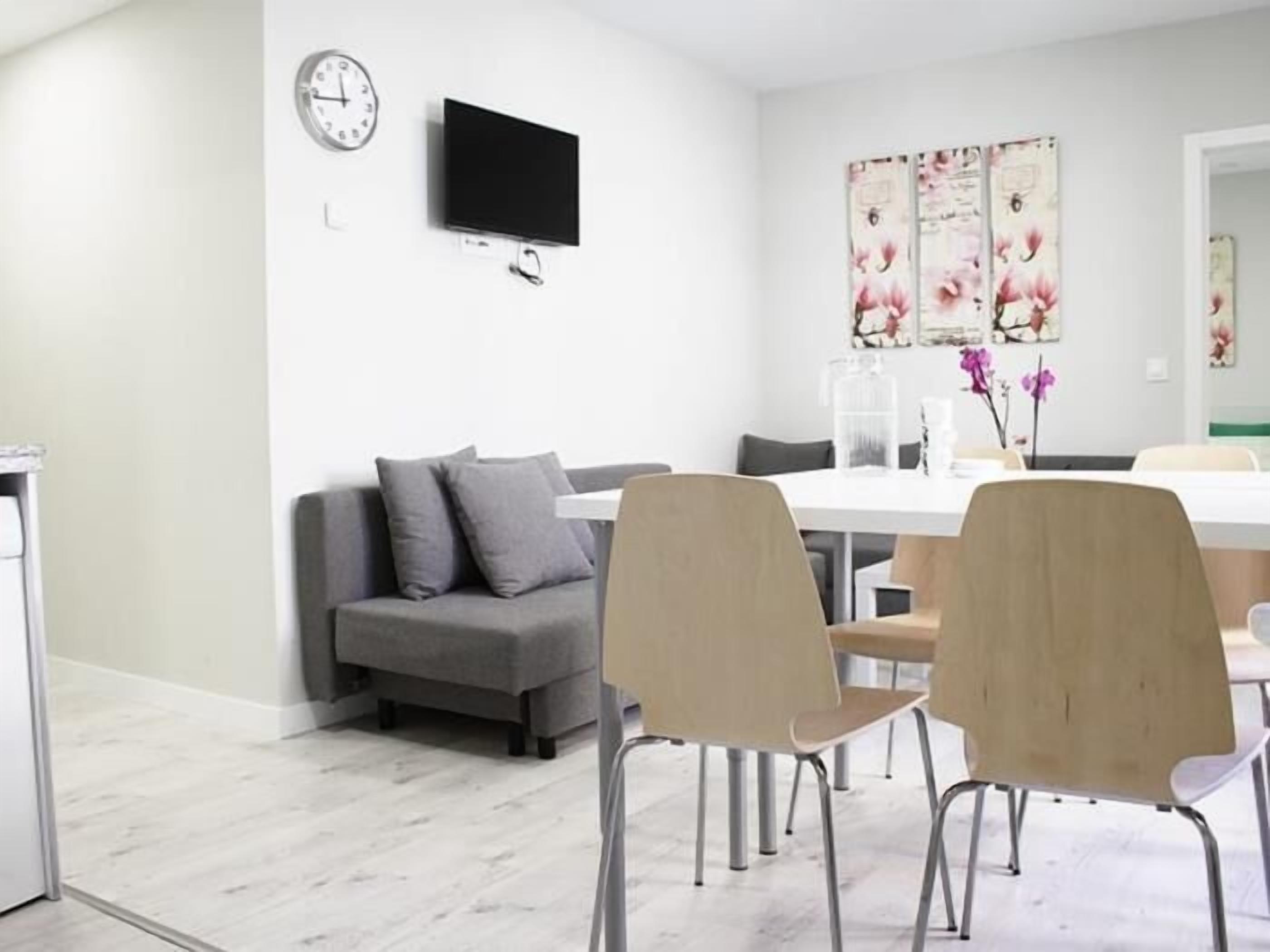 A modern living room with a sofa, chairs, a flat-screen TV, and artwork on the wall.