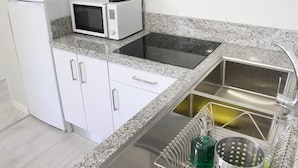 Une cuisine équipée d’un four à micro-ondes, d’un évier et d’appareils électroménagers en acier inoxydable.