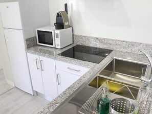A kitchen with a microwave, sink, and stainless steel appliances. - APARTAMENTOS LOGROÑO CENTRO (LOGROÑO)
