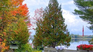 Un bain à remous avec une terrasse en bois, un drapeau et des arbres aux feuilles d’automne.