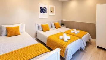 A hotel room with two beds, a wooden floor, and a white radiator.