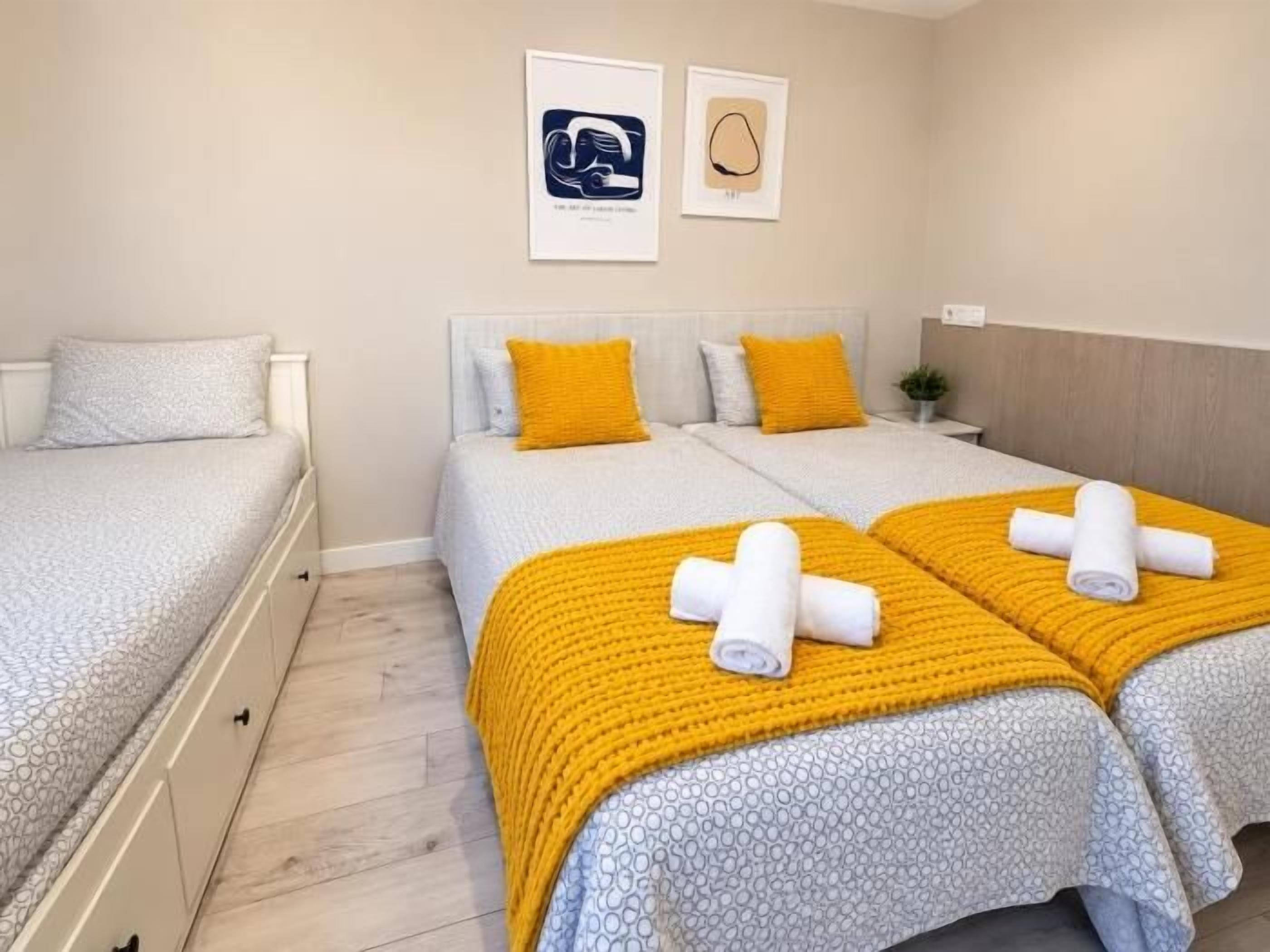 A hotel room with two beds, a wooden floor, and a neutral color scheme.