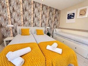 Ein Hotelzimmer mit zwei Betten, einer Schlafcouch, einer Holzvertäfelung und Bildern an der Wand.