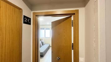 A hallway with a wooden door labeled '2C' leading to a room with a bed and a window.