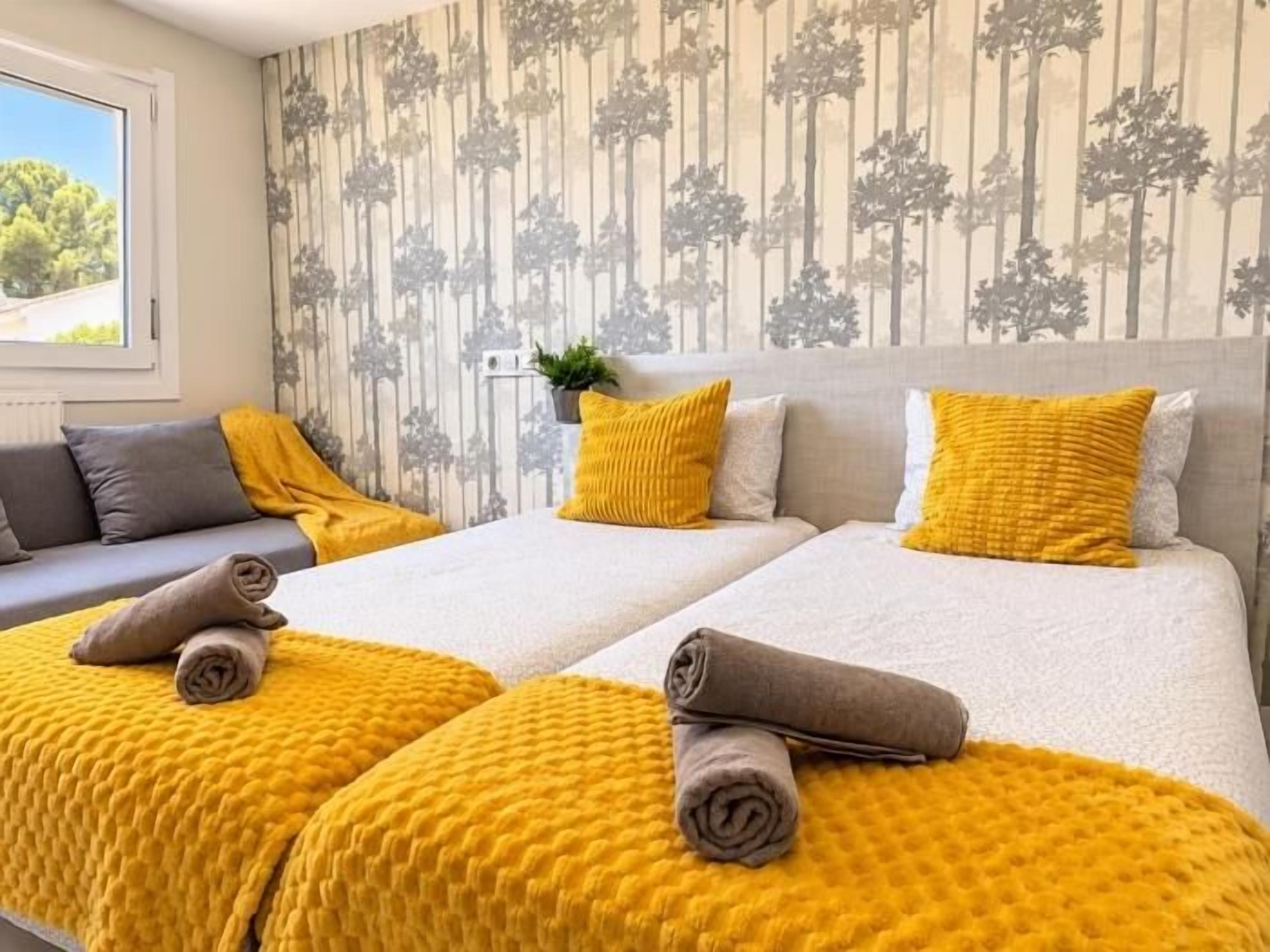 Habitación de hotel con dos camas, un sofá y un ventanal.