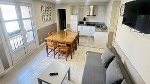 A compact living space with a dining area, kitchenette, and a gray sofa. - APARTAMENTOS LOGROÑO CENTRO (LOGROÑO)
