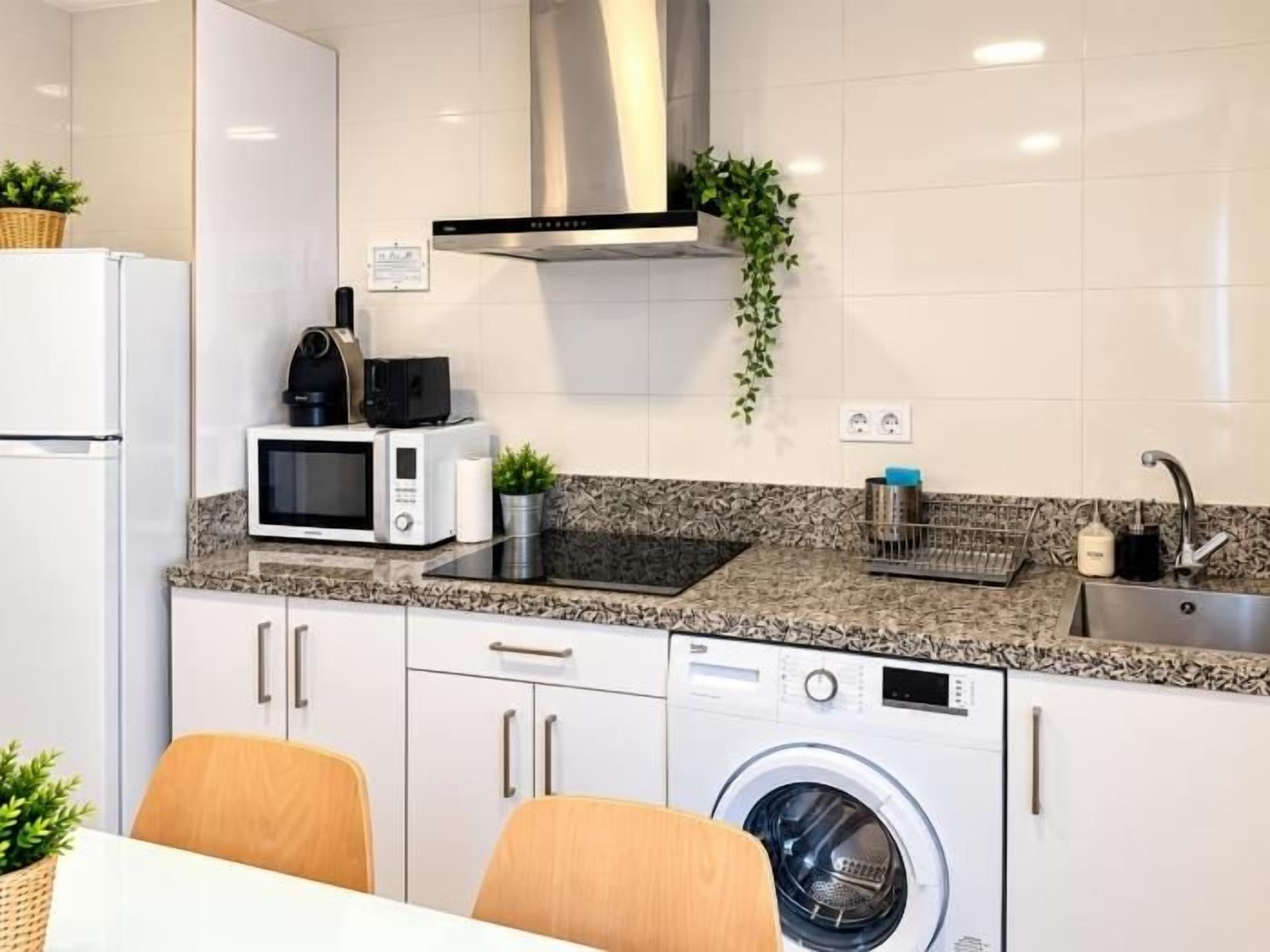 Eine kompakte Küche mit Mikrowelle, Toaster, Spüle und Waschmaschine.