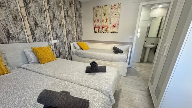 A hotel room with two beds, a marble wall, and a bathroom visible through an open door. - APARTAMENTOS LOGROÑO CENTRO (LOGROÑO)