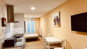 A compact kitchen with a microwave, toaster, and a white dining table with chairs.