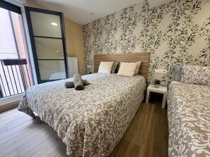 A bedroom with a bed, a nightstand, a potted plant, and a window with a view. - APARTAMENTOS SAN NICOLAS (LOGROÑO)