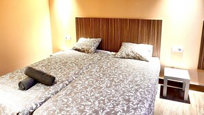 A hotel room with a large bed, two bedside tables, and a wooden headboard. - APARTAMENTOS SAN NICOLAS (LOGROÑO)