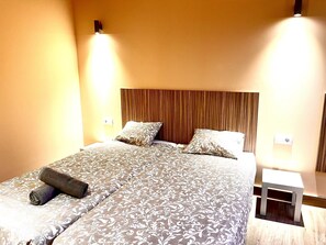 Una habitación de hotel con una cama grande, dos mesitas de noche y un cabecero de madera.