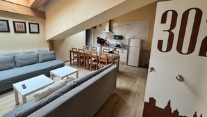 A loft-style apartment with a dining area, kitchenette, and a large window. - APARTAMENTOS SAN NICOLAS (LOGROÑO)