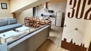 A modern apartment with a dining area, kitchen, and a sofa. - APARTAMENTOS SAN NICOLAS (LOGROÑO)