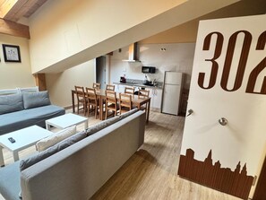 A modern apartment with a dining area, kitchen, and a sofa. - APARTAMENTOS SAN NICOLAS (LOGROÑO)