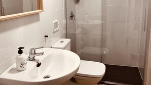 A bathroom with a white sink, toilet, and shower. - APARTAMENTOS SAN NICOLAS (LOGROÑO)