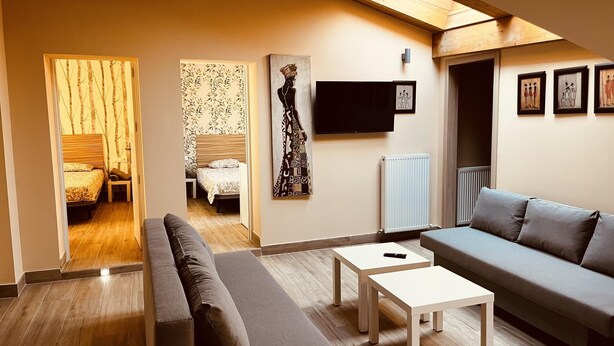A modern living room with a sofa, a coffee table, and a TV mounted on the wall. - APARTAMENTOS SAN NICOLAS (LOGROÑO)