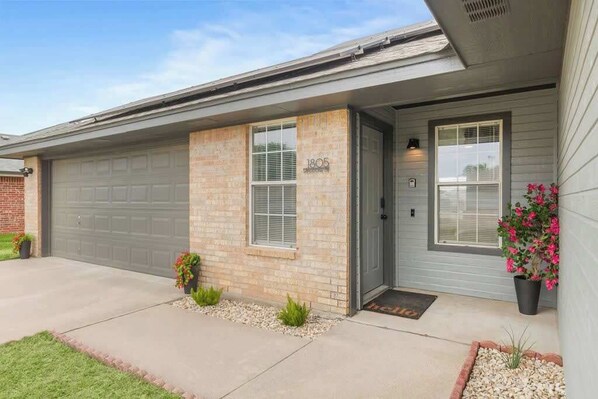 A residential house with a garage, a front door, and a mailbox. - Omni Smart House w/Alexa Voice Control Retreat (Killeen)