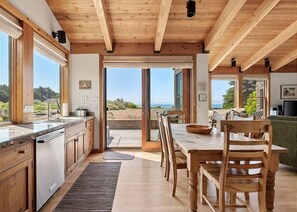 Eine moderne Küche mit Holzbalken, ein Essbereich mit Aussicht und ein großes Fenster.