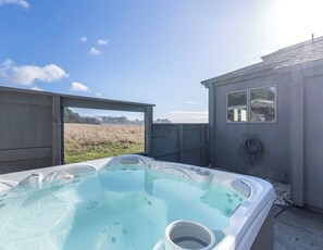 Un bain à remous offrant une vue dégagée sur un champ et un petit bâtiment doté d’une fenêtre.